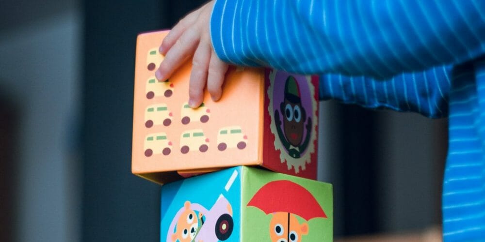 Young boy stacks funny animal comic cardboard boxes. Early childhood motor skills.