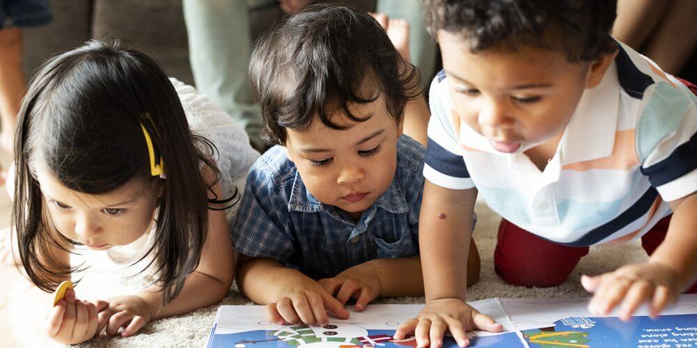 Children reading a book on the floor Children reading a book on the floor