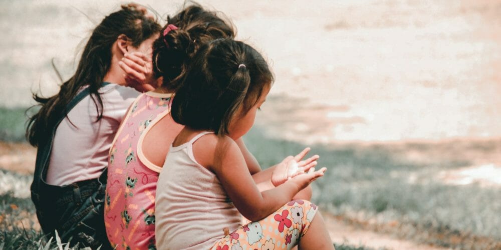 three children sitting on grass