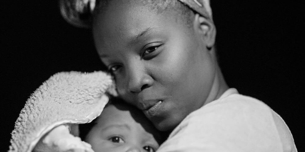 A mother holding her newborn, photo by Andrae B. Ricketts