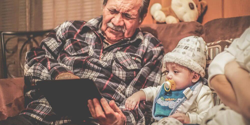 man-in-plaid-shirt-holding-baby-stockpack-unsplash Older man in plaid shirt reading to baby