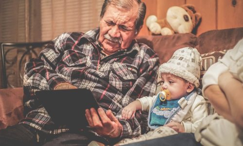 Older man in plaid shirt reading to baby