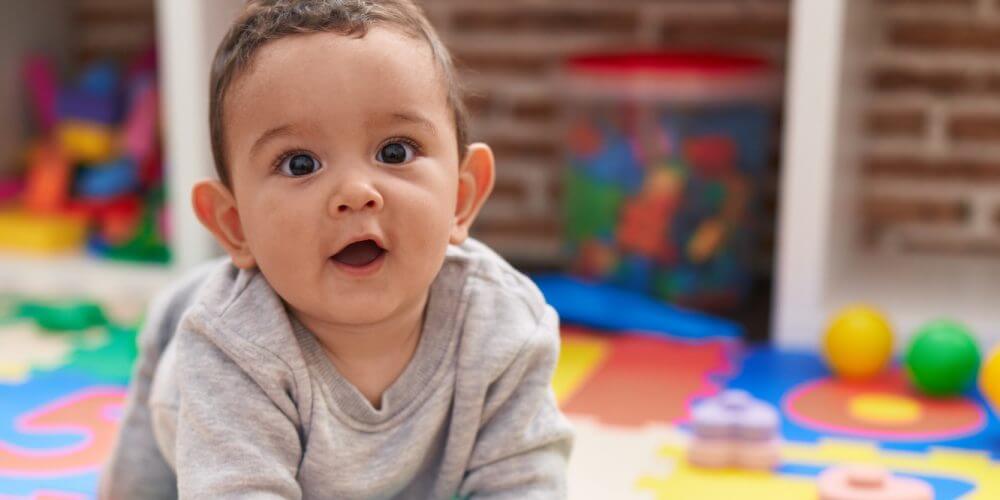 Adorable hispanic baby crawling on floor at kindergarten