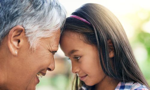 Little girl standing face to face with her grandmother while enjoying the day outdoors