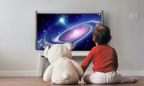 Toddler and his teddy bear watching tv