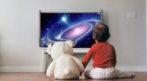 Toddler and his teddy bear watching tv