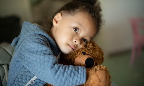 Girl toddler hugging a suffed teddy bear toy