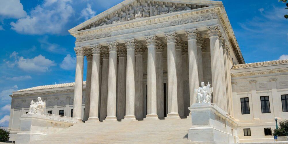Photo of the Supreme Court of the United States located in Washington DC with a blue sky and clouds in background. Supreme Court of the United States located in Washington DC which interprets laws. It is the Judicial Branch of the US government.